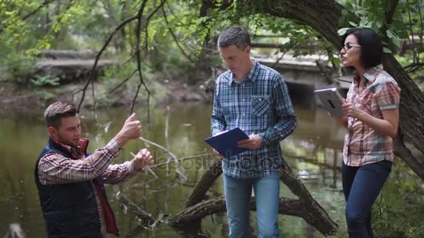 Трое ученых изучают воду в озере — стоковое видео