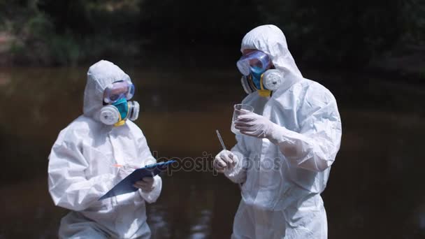 Two ecological workers in biohazard discuss water — Stock Video