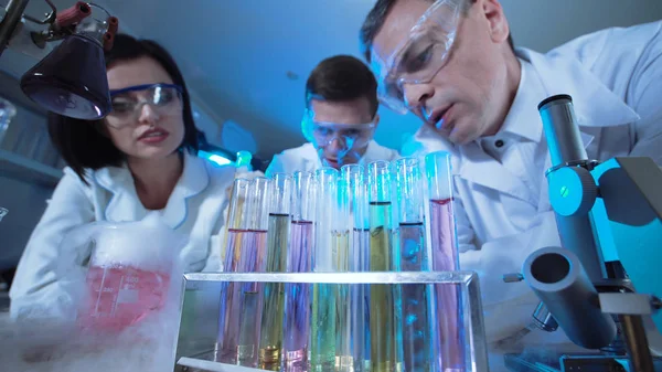 Cientistas observando reações em tubos de ensaio — Fotografia de Stock