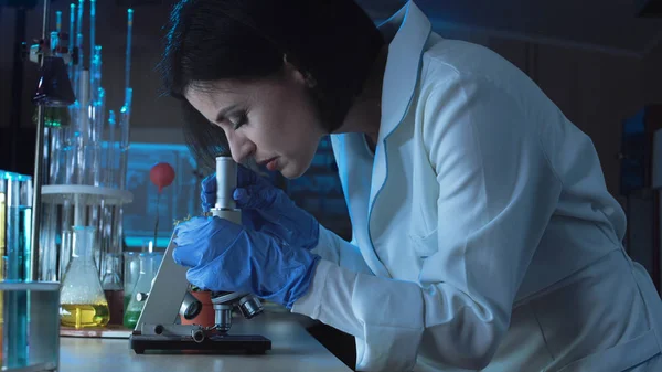 Jovem cientista olhando para baixo um microscópio — Fotografia de Stock