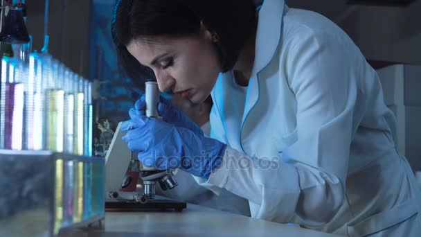 Young female scientist looking down a microscope — Stock Video