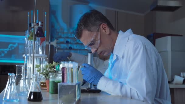 Man in medical gown looking at microscope — Stock Video