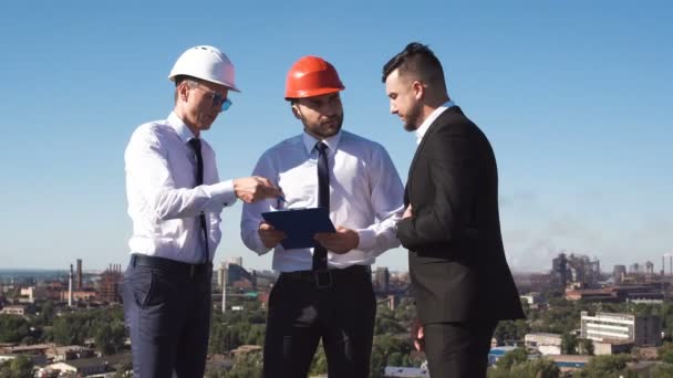 Tres hombres de negocios en la charla de sombrero duro — Vídeo de stock