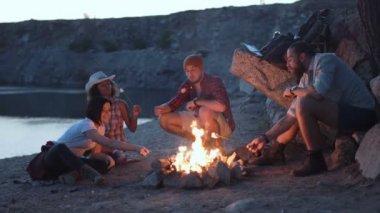 Neşeli arkadaşları kamp ateşi etrafında rahatlatıcı