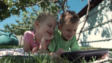 Neşeli çocuklar tablet bahçe içinde izlerken