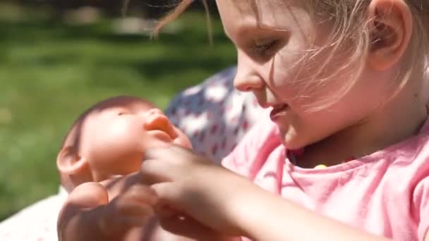 Meisje spelen met baby pop in achtertuin — Stockvideo