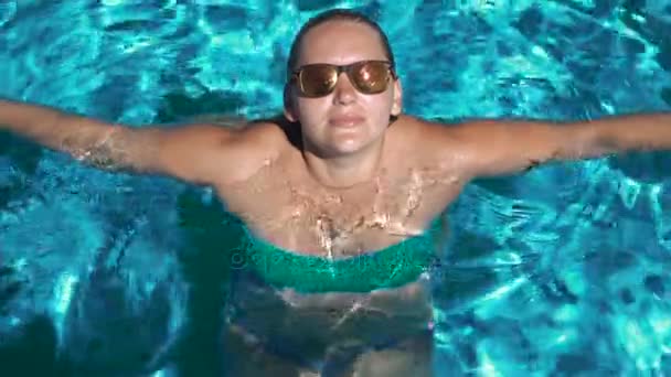 Женщина в солнечных очках расслабляется в бассейне . — стоковое видео