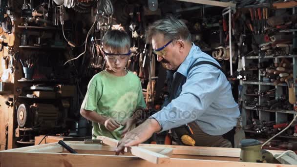 Карпентер з онука, працюючи в майстерні — стокове відео