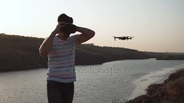 Uomo che controlla drone sulla riva del fiume — Video Stock