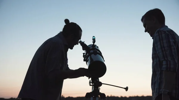 People using telescope in dawn