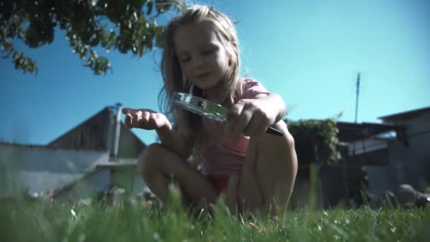 Girl with loupe on lawn — Stock Video