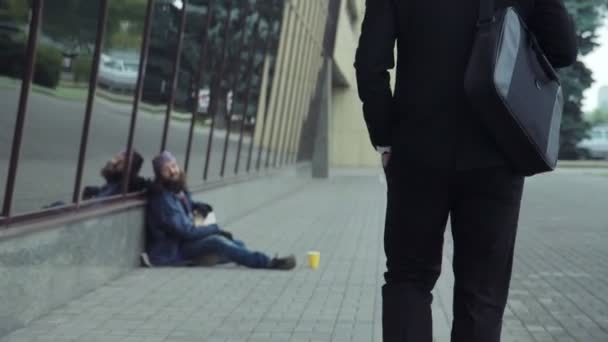 Úspěšný muž dávat peníze na bezdomovce — Stock video