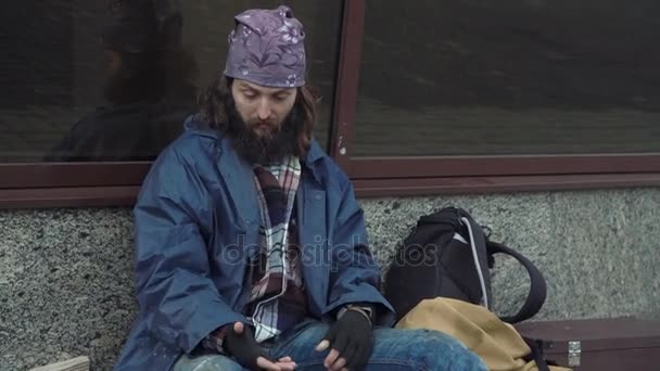 Ένας μεθυσμένος άστεγος άντρας κάθεται στο δρόμο. — Αρχείο Βίντεο