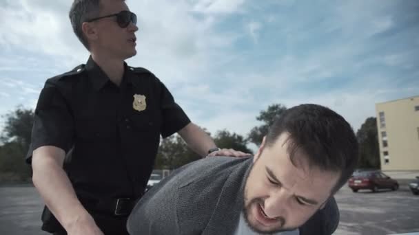 Policía arrestando a criminal en estacionamiento — Vídeos de Stock