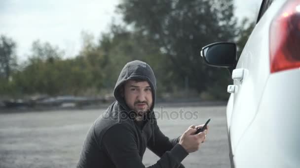 Ladrón irrumpiendo en el coche usando el teléfono móvil — Vídeo de stock