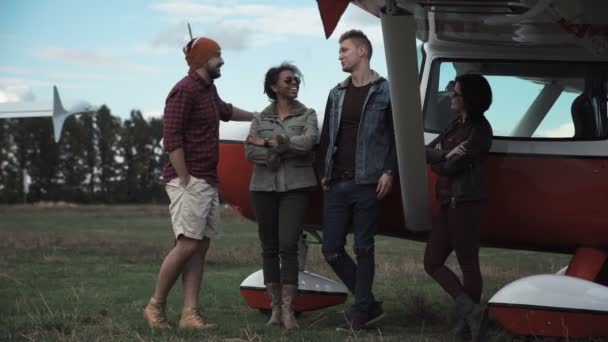 Groep vrienden praten naast vliegtuig — Stockvideo