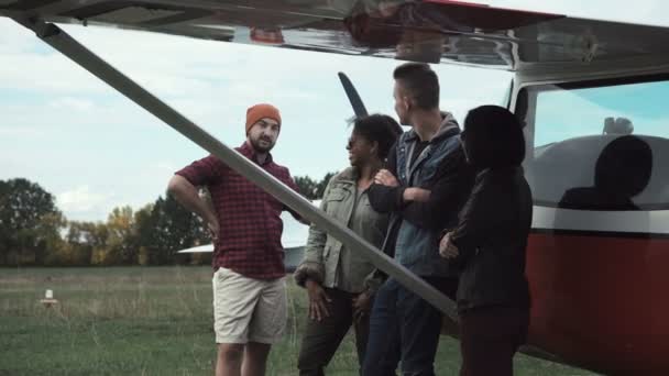 Group of friends talking next to airplane — Stock Video