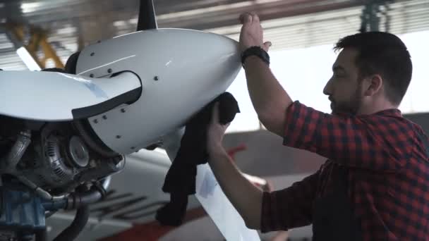 Man cleaning aircraft propeller in hangar — Stock Video