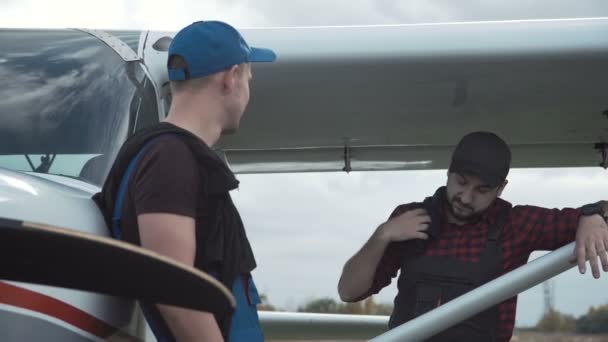 Pilot och mekaniker som chattar på ett flygfält — Stockvideo