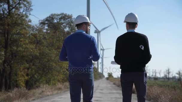 Dois engenheiros caminhando em direção ao parque eólico — Vídeo de Stock
