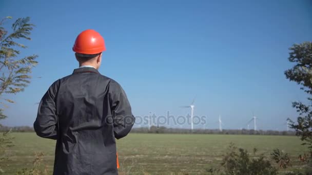 Инженер наблюдает за ветряными турбинами через бинокль — стоковое видео