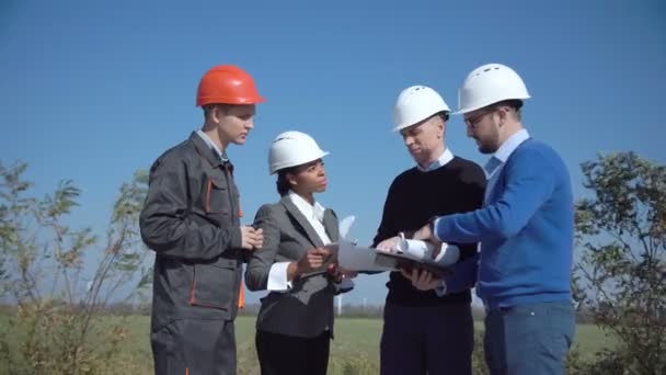 Cuatro ingenieros de pie en campo abierto — Vídeo de stock