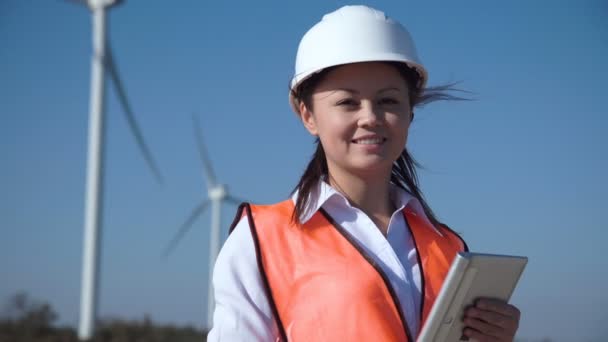 Sorridente ingegnere donna in piedi contro parco eolico — Video Stock