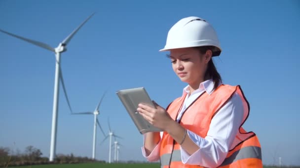 Frau mit hartem Hut gegen Windkraftanlage — Stockvideo