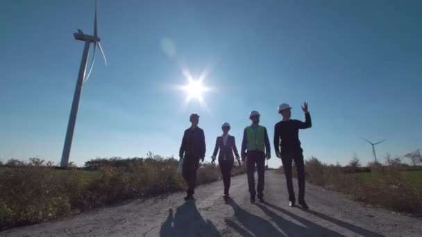 Gruppe von Ingenieuren läuft am Windpark entlang der Straße — Stockvideo
