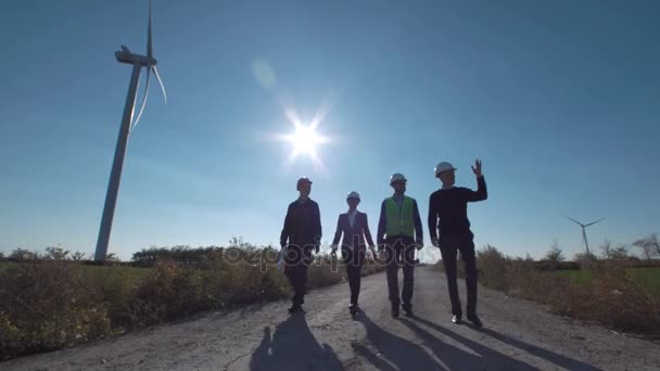 Groupe d'ingénieurs marchant le long de la route au parc éolien 