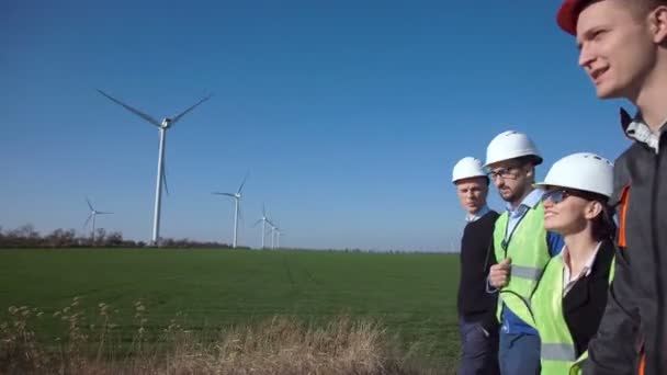 Grupo de ingenieros caminando contra parque eólico — Vídeo de stock