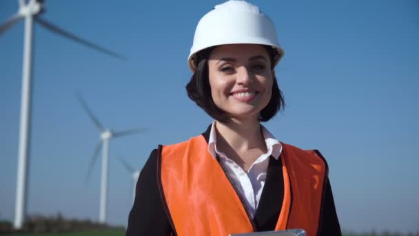 Ingeniera sonriente de pie contra parque eólico — Vídeo de stock