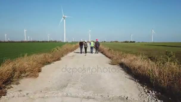 Группа инженеров, идущих против ветровой электростанции — стоковое видео