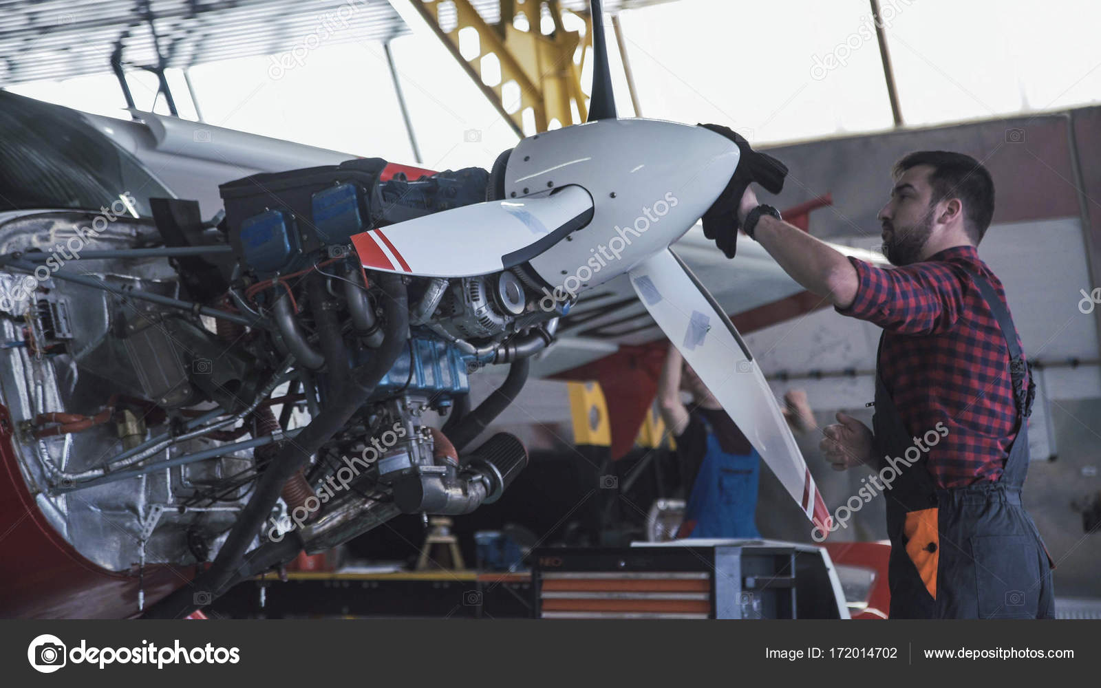 man cleaning aircraft propeller in hangar stock photo