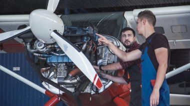Two mechanics working on a small aircraft clipart