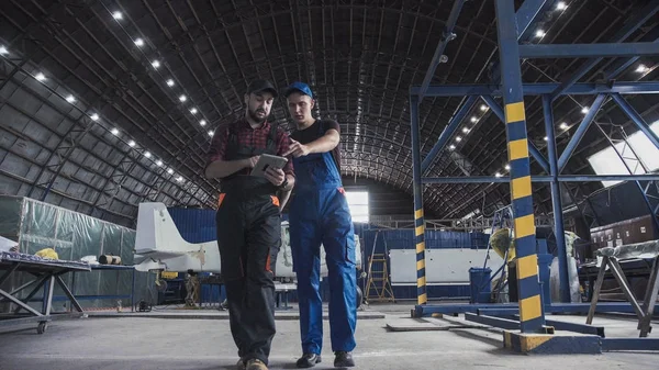 Twee boordwerktuigkundigen lopen door een hangar — Stockfoto