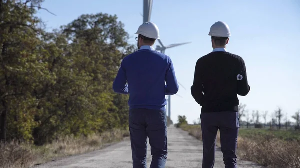 Двоє інженерів йдуть на вітроелектростанцію — стокове фото