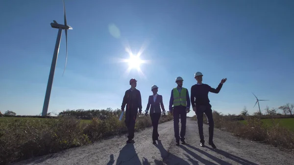Група інженерів, що йдуть по дорозі на вітроелектростанції — стокове фото
