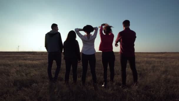 Група людей, що стоять проти заходу сонця — стокове відео