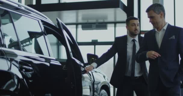 セールスマン招待の潜在的なバイヤーは車に乗る — ストック動画
