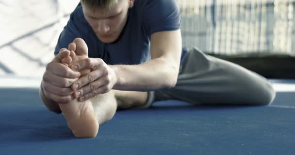 Sportman die zich uitstrekt in sportschool — Stockvideo