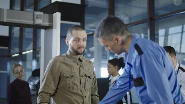 Flygplats anställd kontrollera passagerare med metalldetektor — Stockfoto