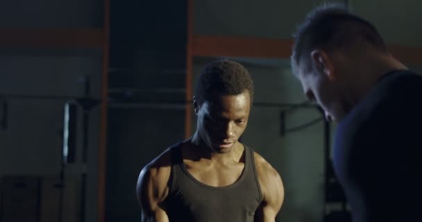 Trainer unterstützt schwarzen Mann beim Heben von Gewichten — Stockvideo