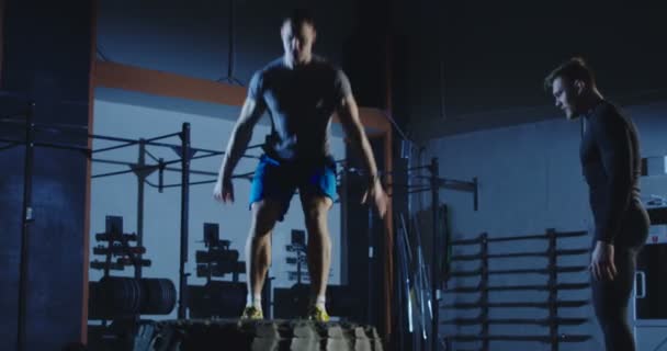 Hommes sportifs multiethniques s'entraînant ensemble dans une salle de gym sombre — Video