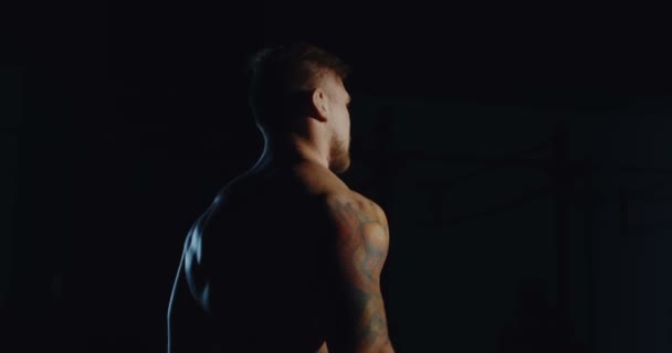 Мускулистый мужчина тренируется с гантелями в спортзале — стоковое видео