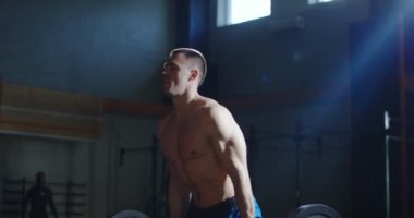 Güçlü gömleksiz atlet güneşli spor salonunda halter kaldırma