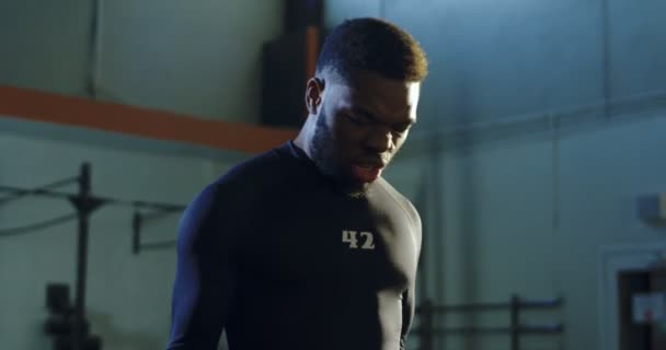 Сильный черный мужчина поднимает гири в спортзале — стоковое видео