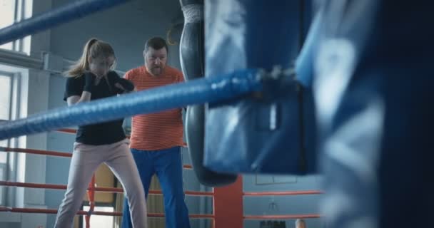 Meisje boxing bokszak met trainer — Stockvideo