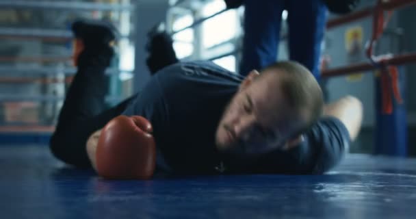 Omedvetna boxare i handskar liggande på ringen — Stockvideo