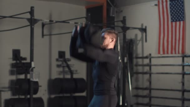 Treinamento de homem muscular com sandbag no ginásio — Vídeo de Stock